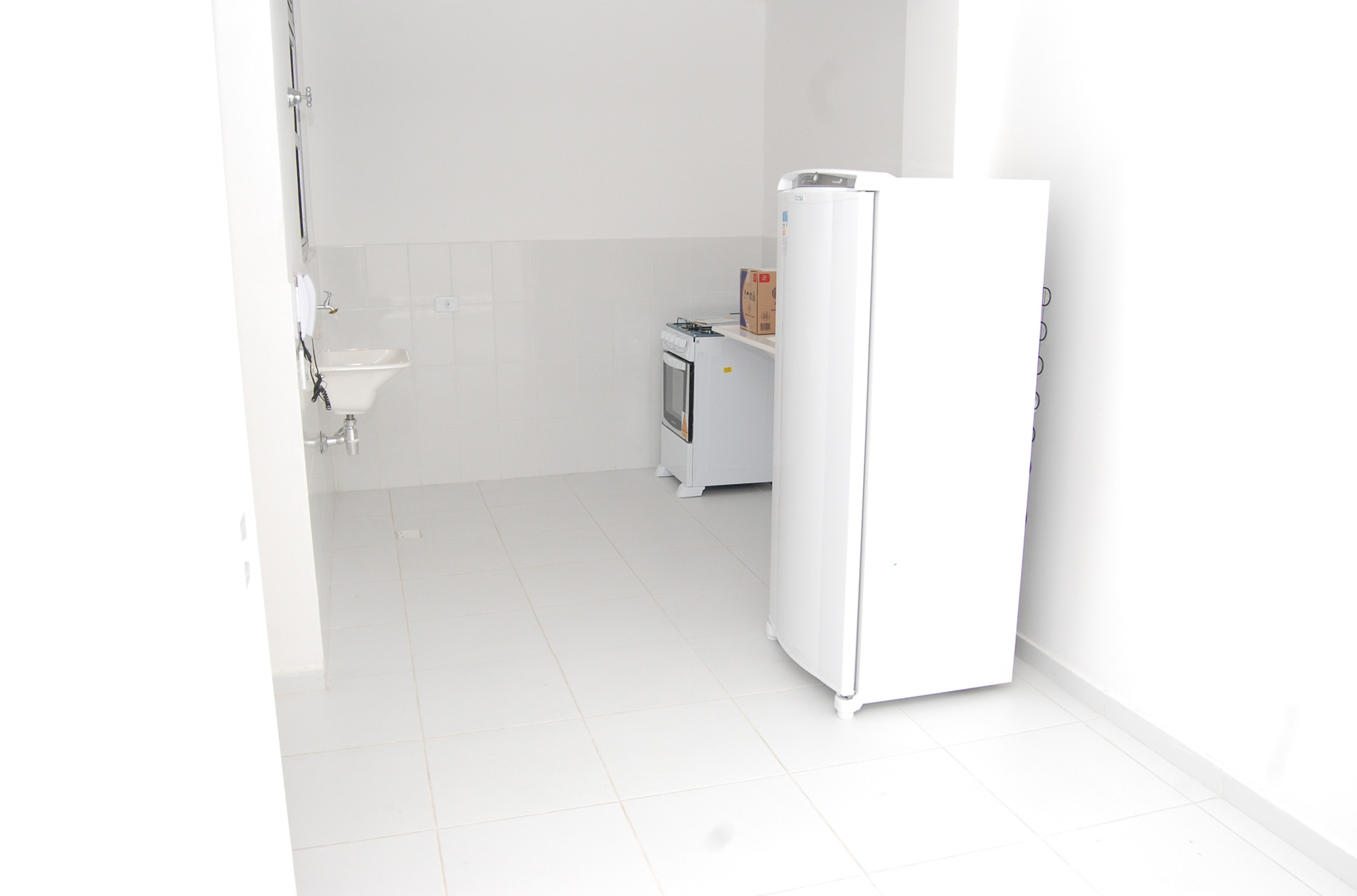 Imagem de dentro de uma das unidades, mostrando uma geladeira e um fogão que foram doados para os moradores