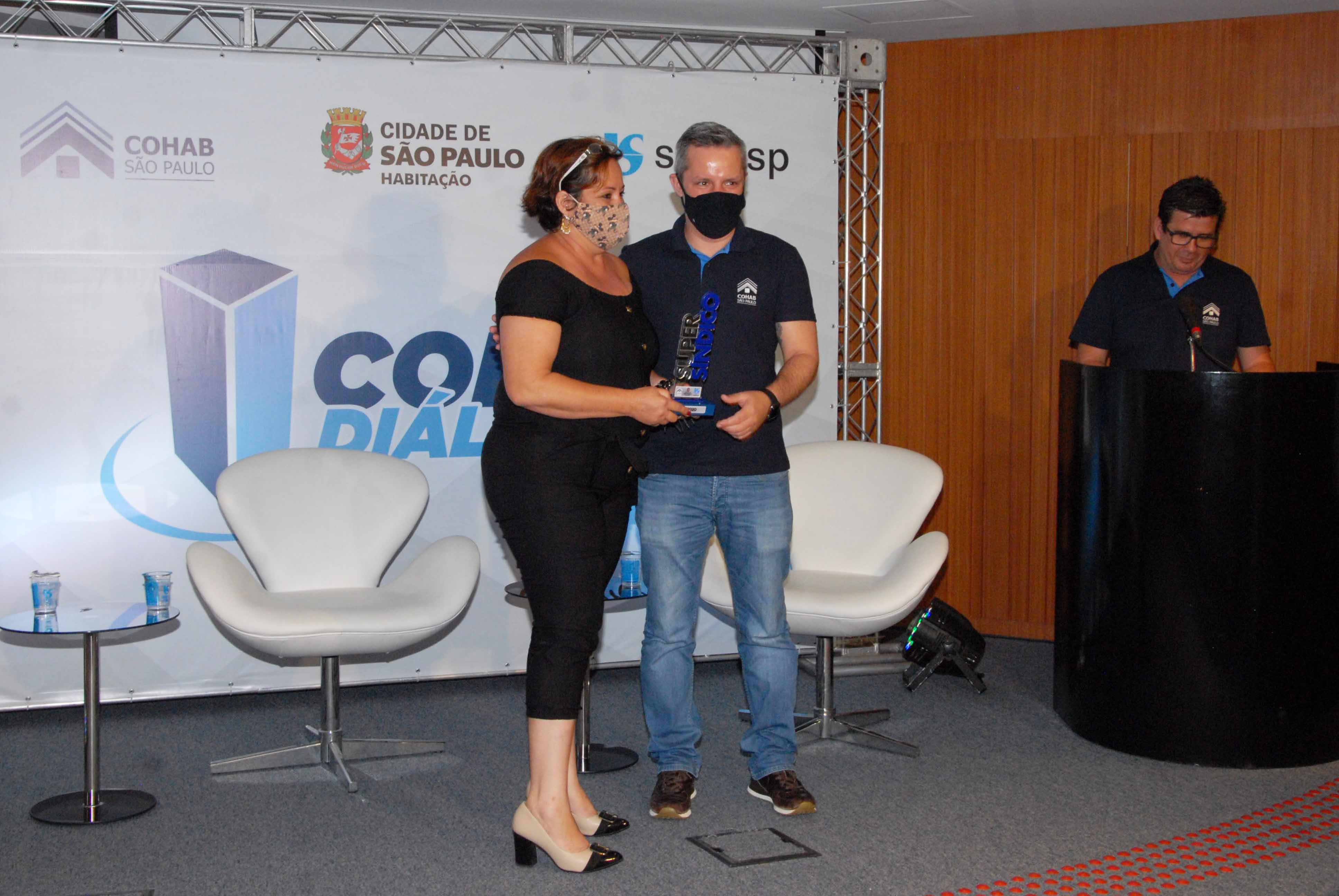 Presidente da Cohab Luigi Lazzuri Netto entregando o troféu para uma síndica. 