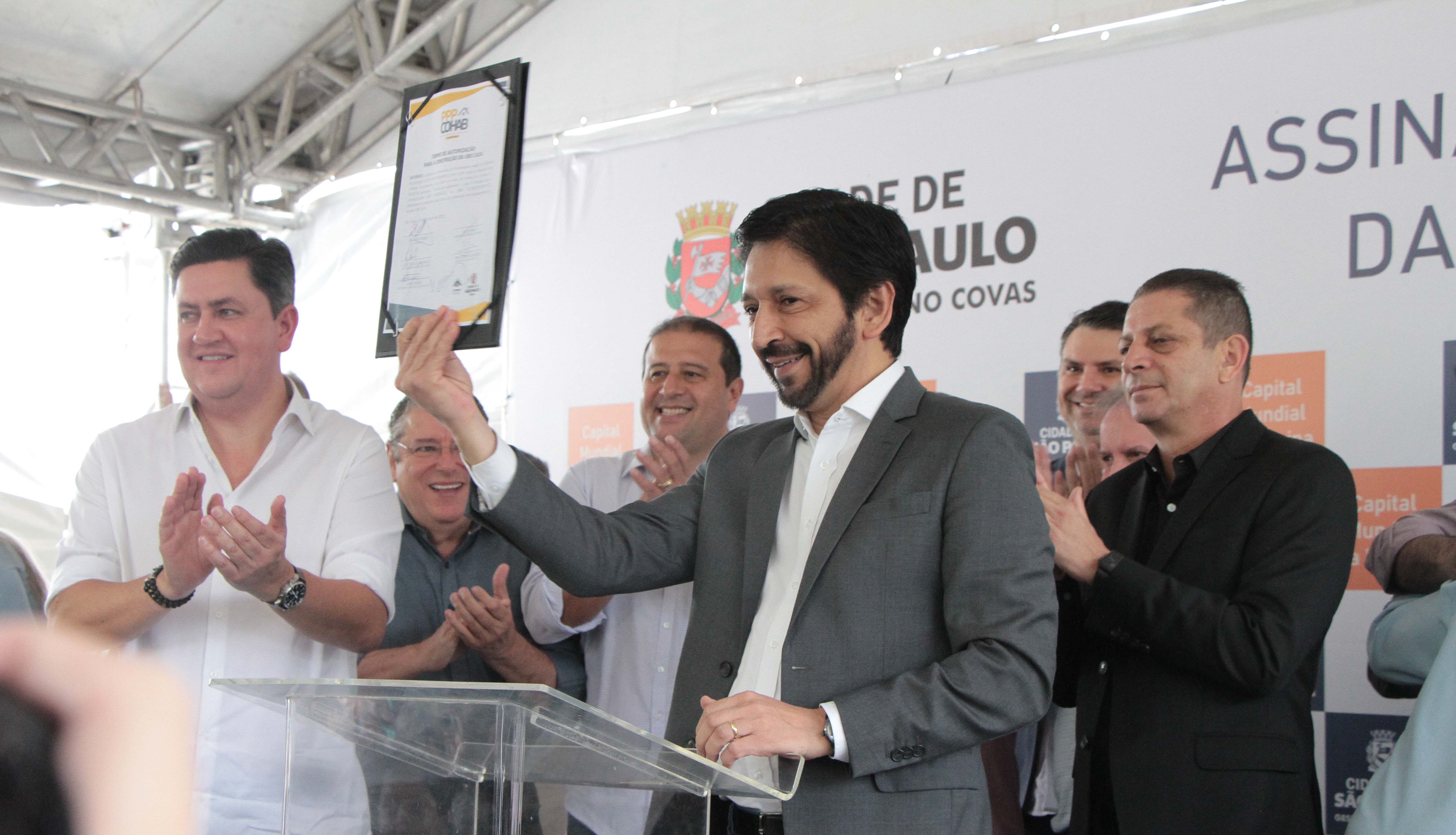 Prefeito Ricardo Nunes mostra o documento assinado pelas autoridades para o público presente