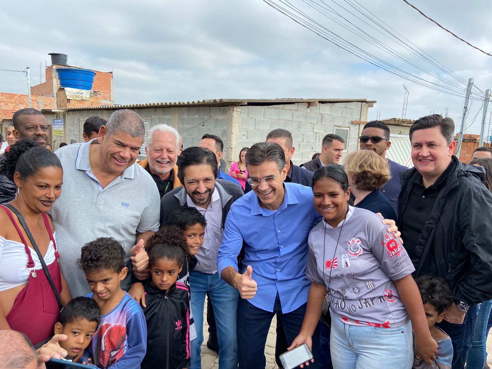 Milton Leite, Ricardo Nunes, Rodrigo Garcia e Alex Peixe posam para a foto junto com uma família composta pela mãe e mais 5 crianças